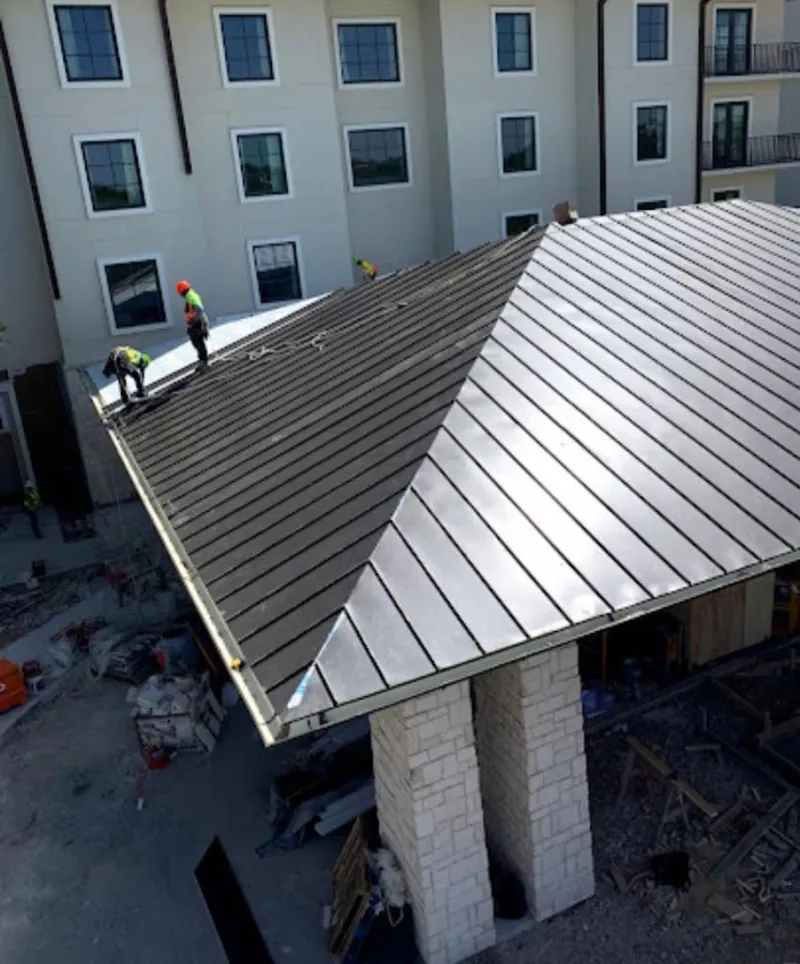 Crew installing standing seam metal roof panels on a commercial project in Rosamond